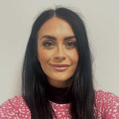 A woman with long, dark hair smiles at the camera