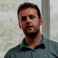 A man wearing a checked shirt gives a talk