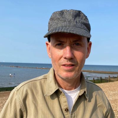 A person wearing a shirt and a striped hat looks at the camera