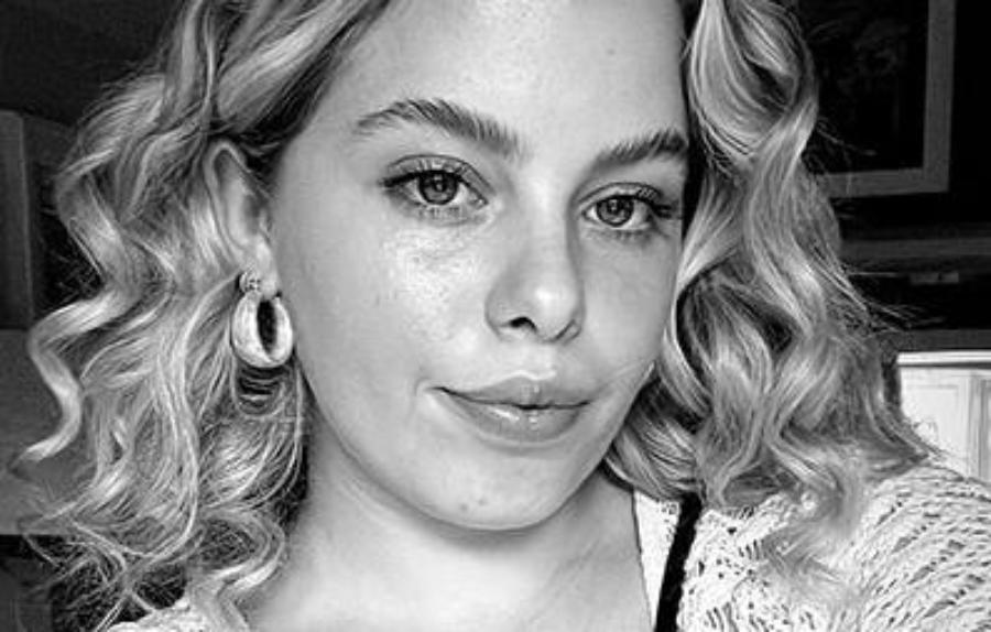 A person with blonde curly hair looking at the camera