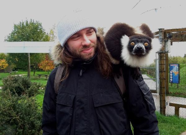 Smiling man with a lemur on his shoulder