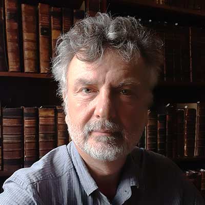 A man stands in front of a bookcase