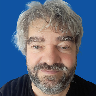 A PHD student smiling against a blue background