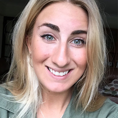 A close up photo of a woman with blue eyes and blonde hair smiling at the camera.