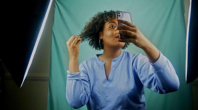 Woman posing for a selfie whilst having her photo taken professionally