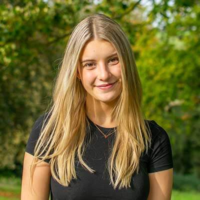 A person with long blonde hair smiles at the camera