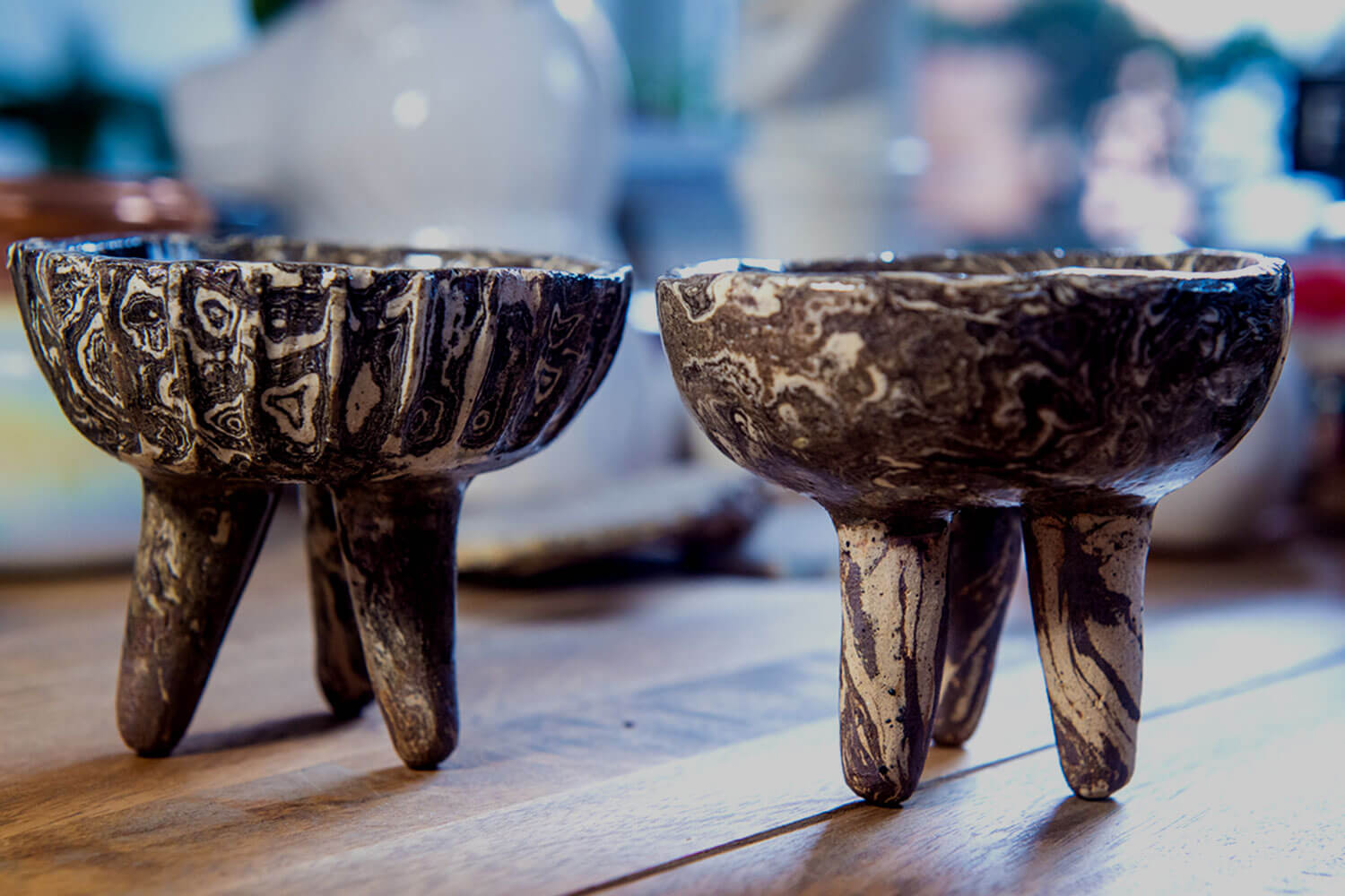 Two decorative ceramic bowls, each balanced on three legs