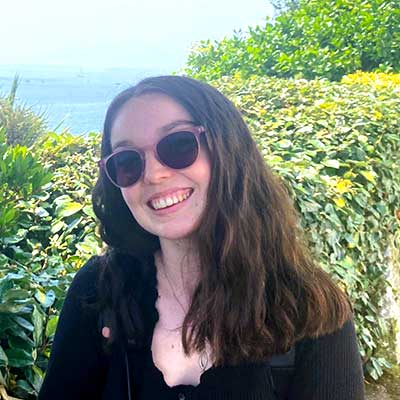 A person wearing sunglasses smiles at the camera