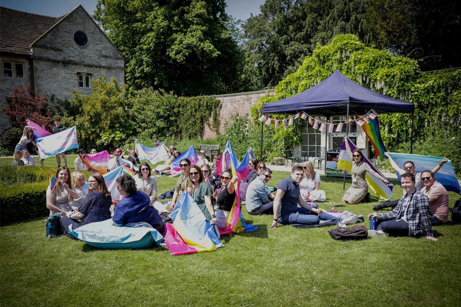 Students and staff sitting on the lawns of the Italian gardens with rainbow Pride flags