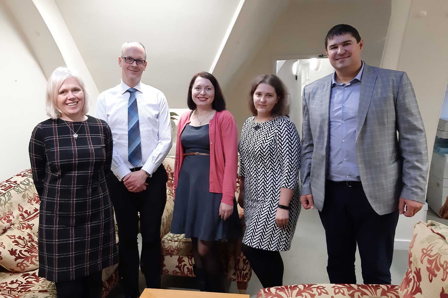 Five people stand and smile at the camera