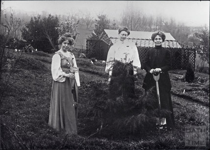 Old photograph of three women in vintage dress planting a tree. One is Emmeline Pankhurst