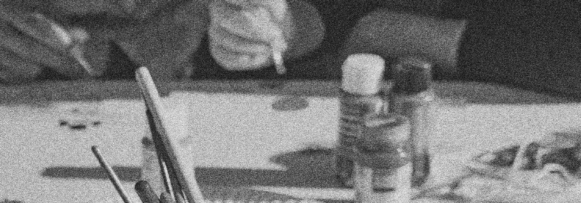 Close up in grainy greyscale of desk with art tools as in a classroom