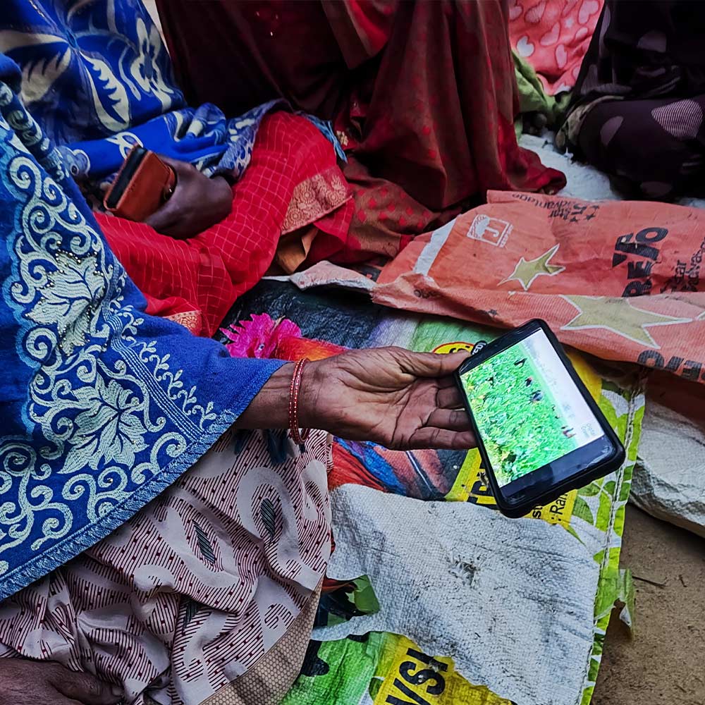 View of woman holding mobile phone sitting on colourful cloths
