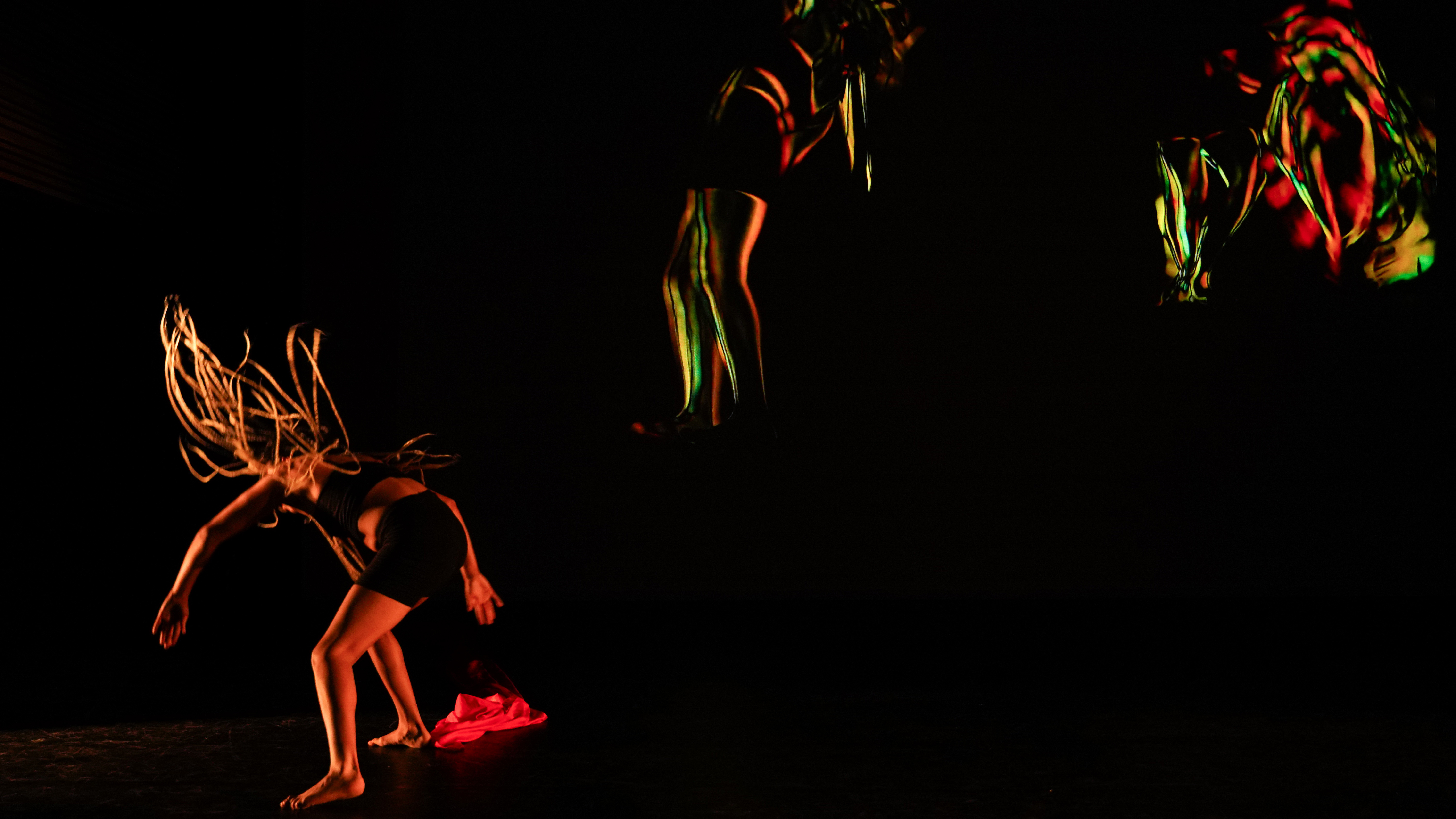A performer on stage pauses after a somersault, digital images show snapshots of the somersault in the background