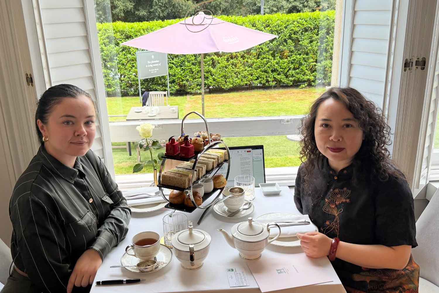 Two-women-sitting-at-a-table-by-a-window-eating-a-cream-tea