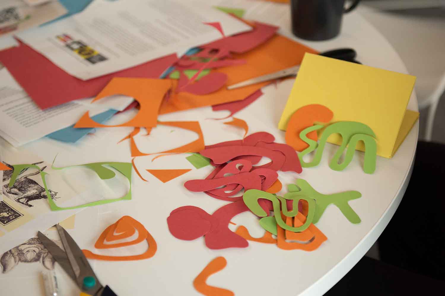 Table with cut out coloured pieces of card in creative workshop