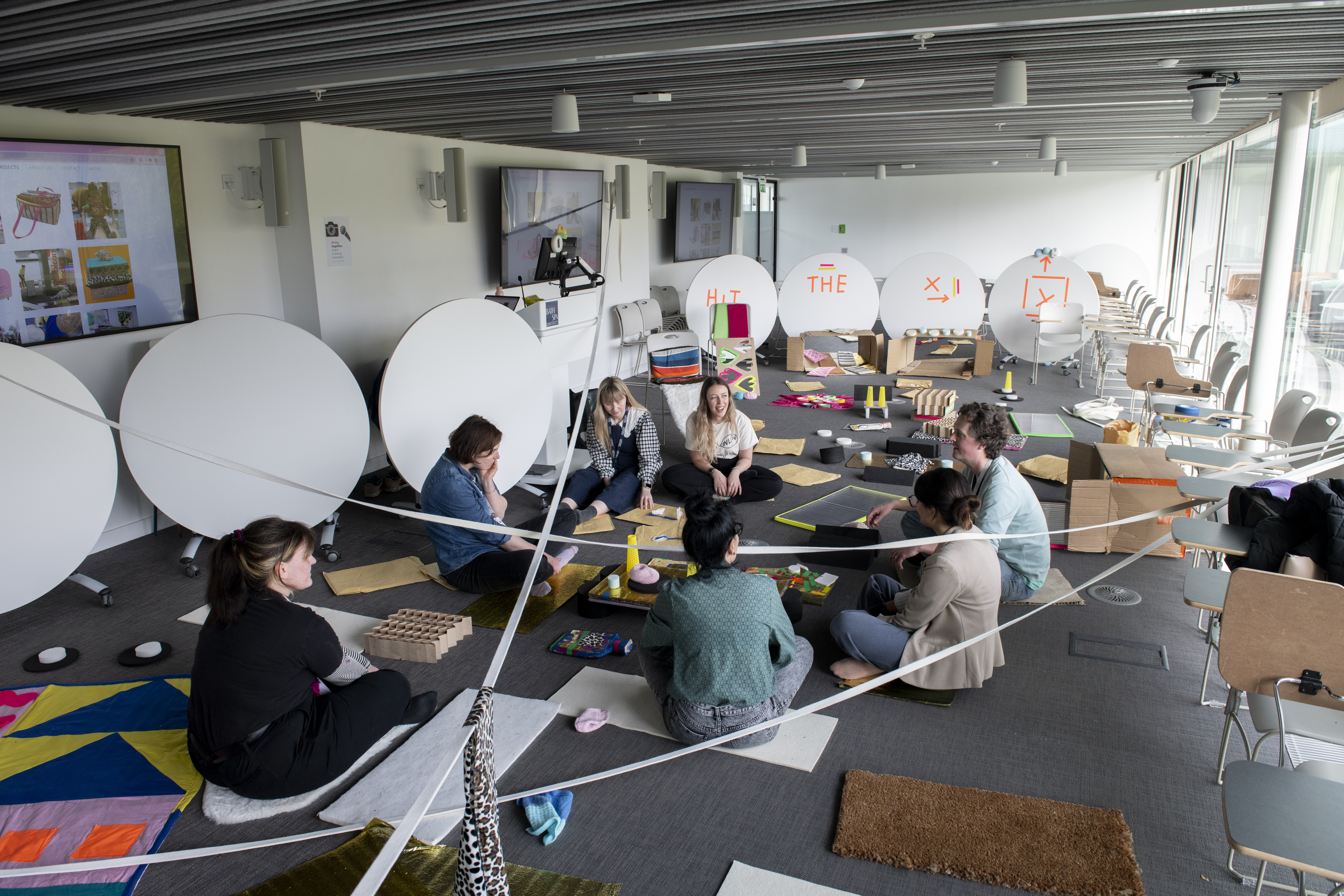 A group of artists sit on the floor to work on a group project