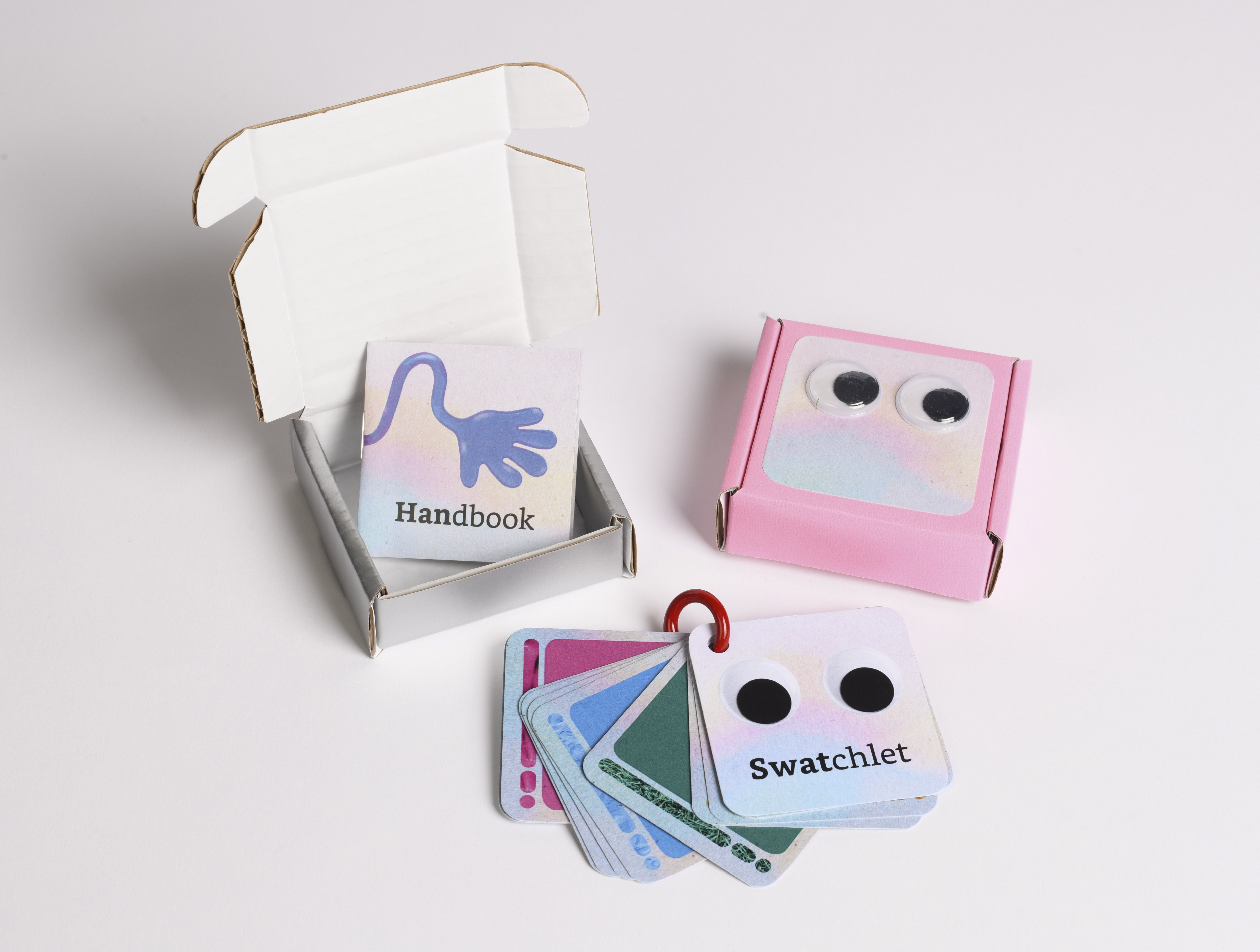 A set of pastel coloured printed cards in a pink box