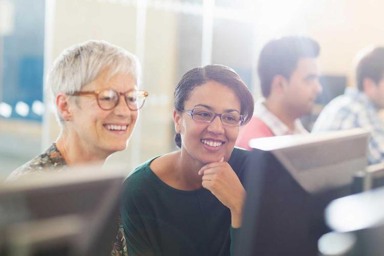 Two adults look at a computer monitor