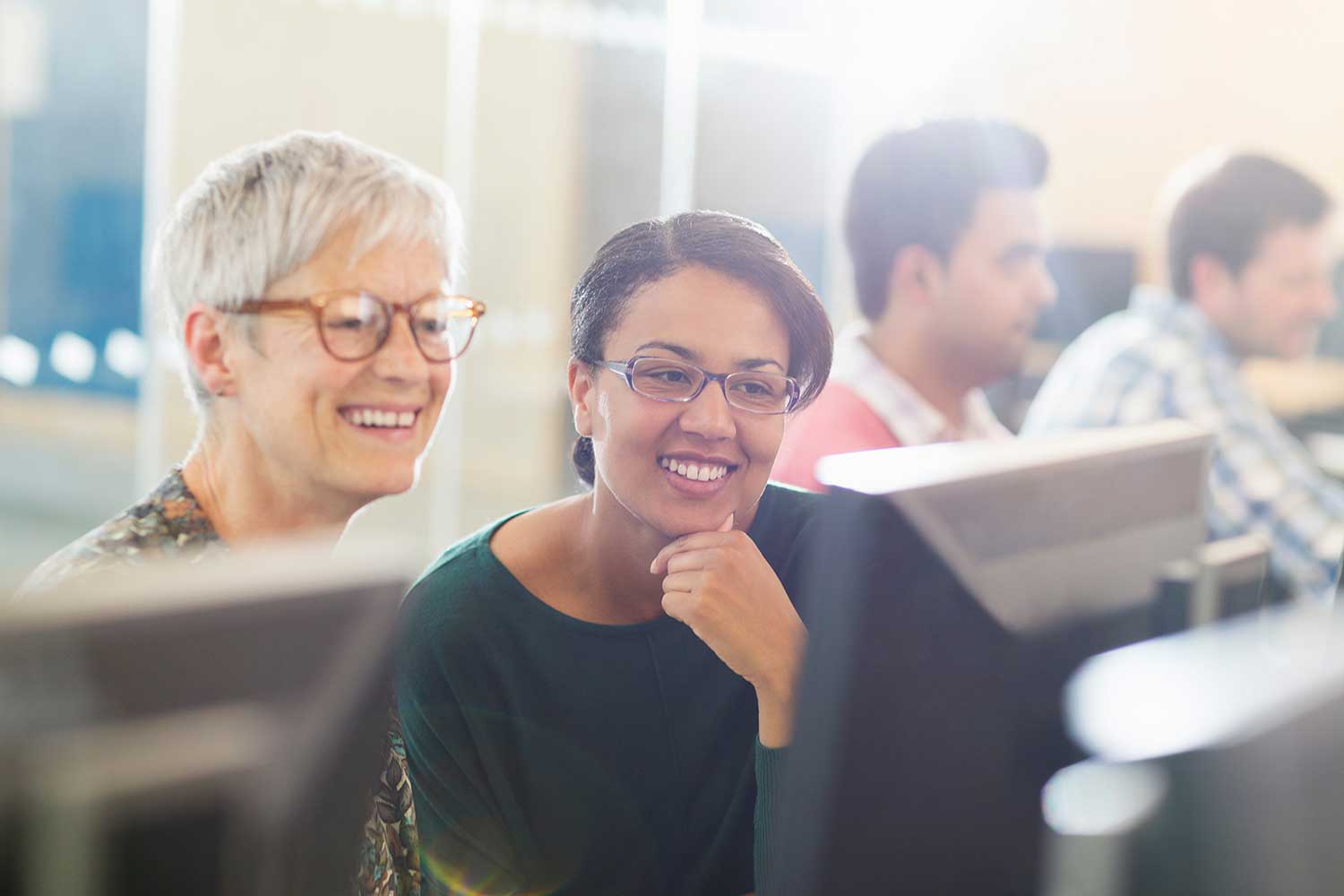 Two adults look at a computer monitor