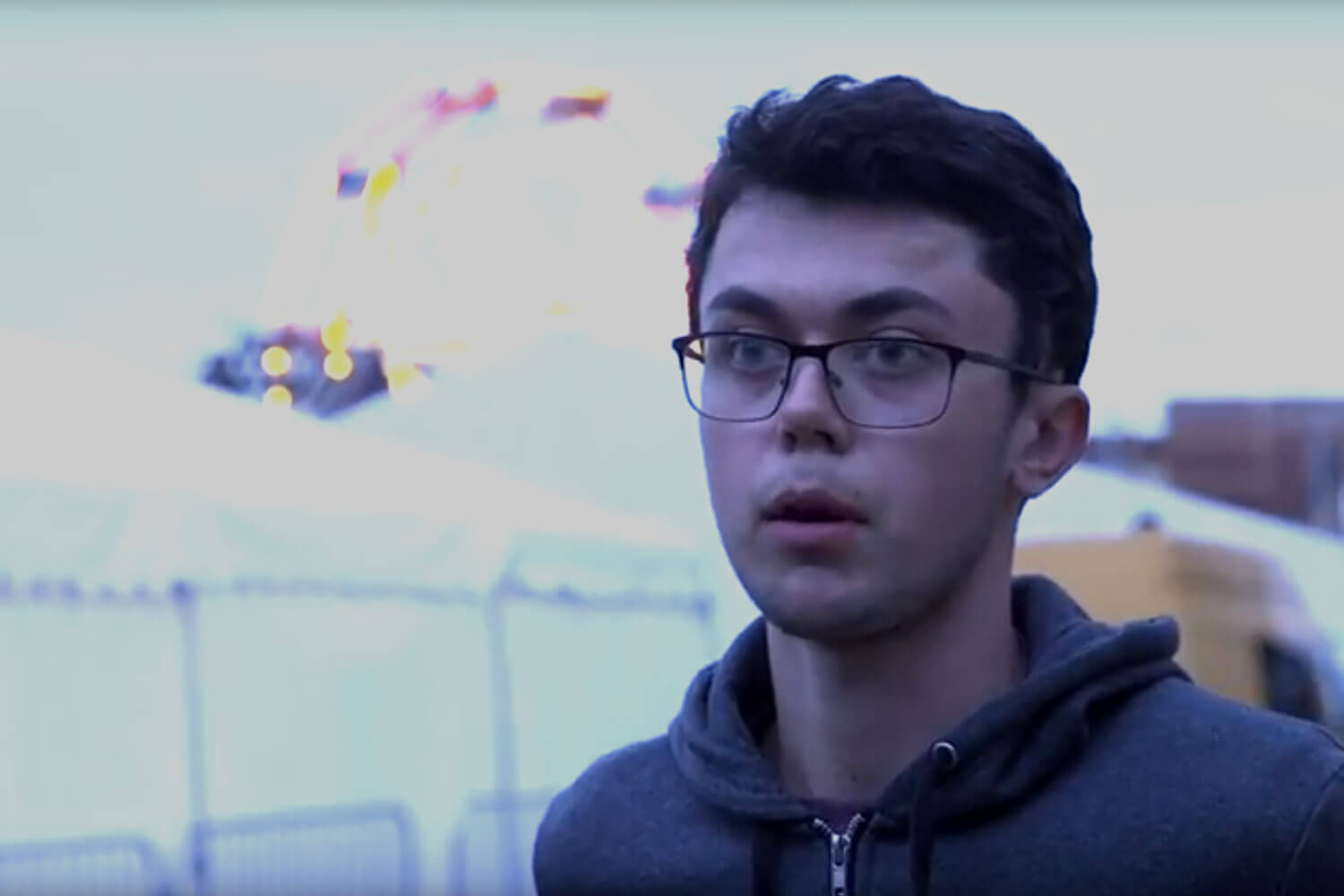 Student talking with ferris wheel and tents in the background