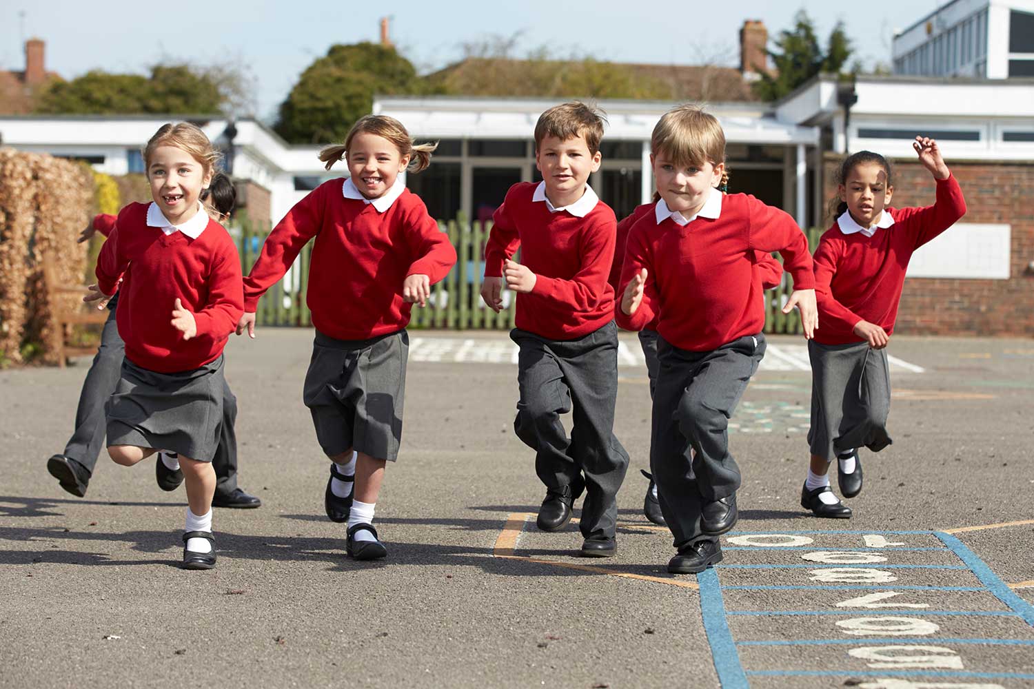Young children wearing school uniform run around a playground