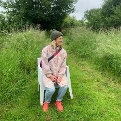 image of someone in a coat and hat sitting on a chair in a field