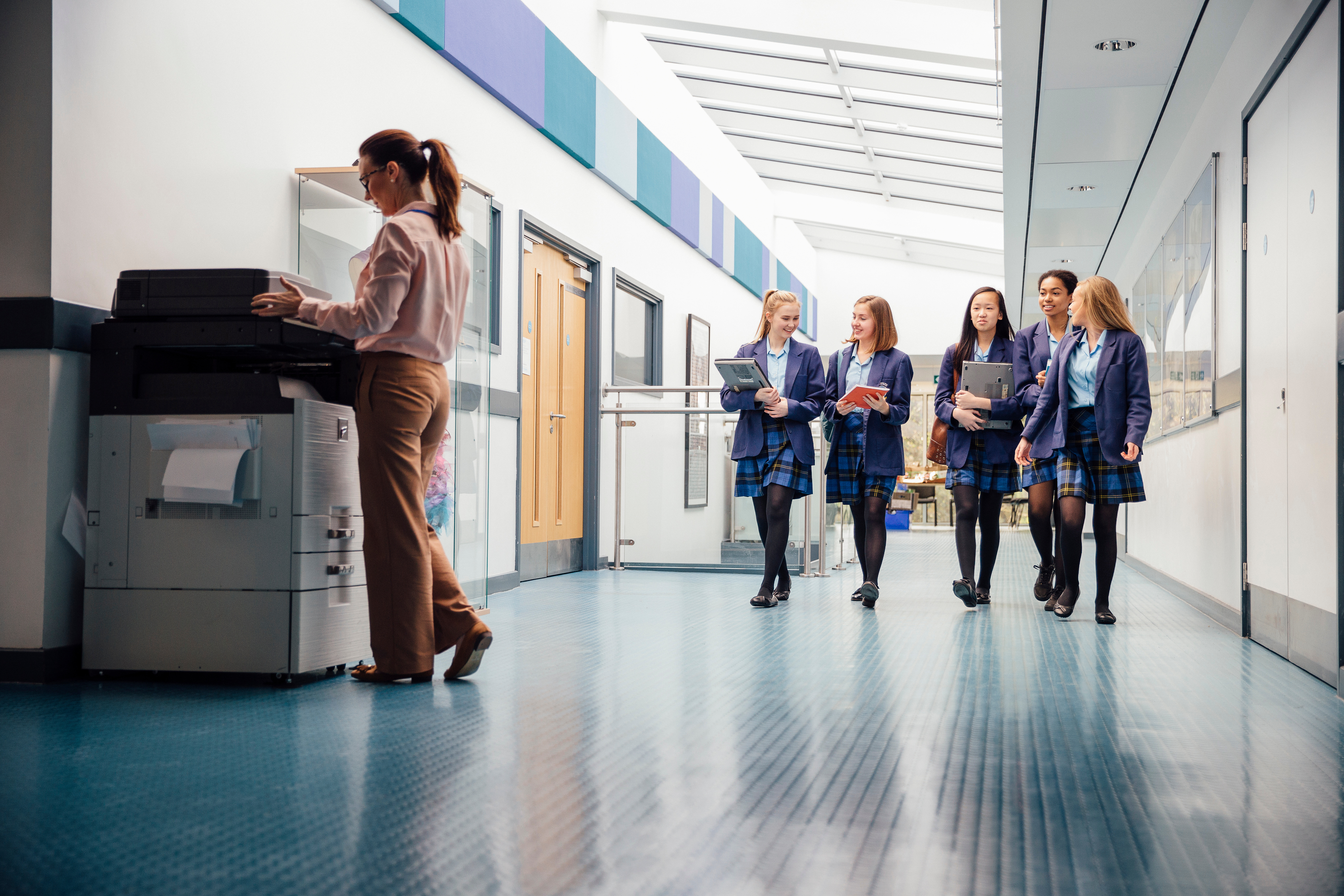A group of secondary school pupils walk down a school corridor