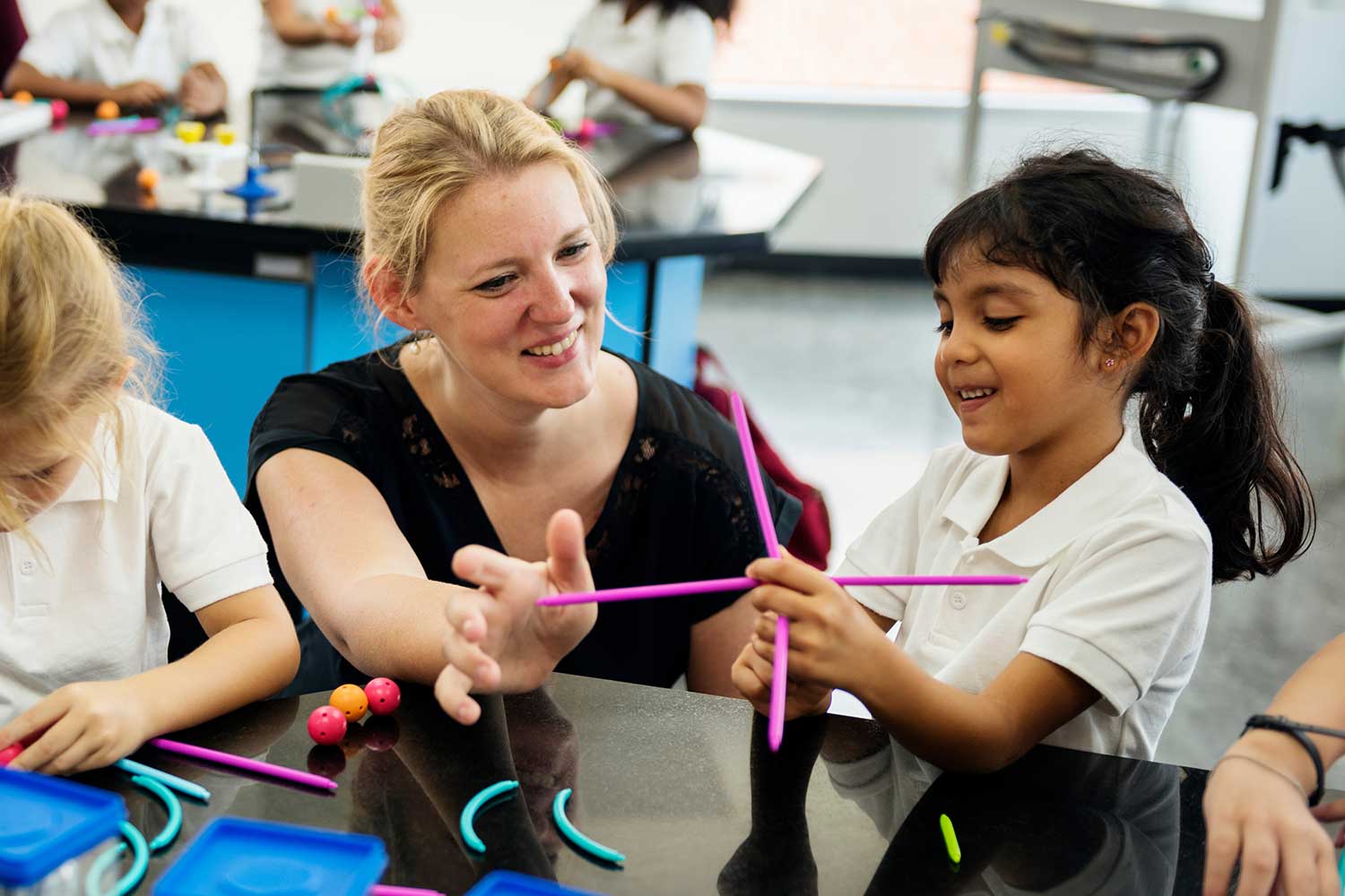 An adult crouches down to help a child with a science related task