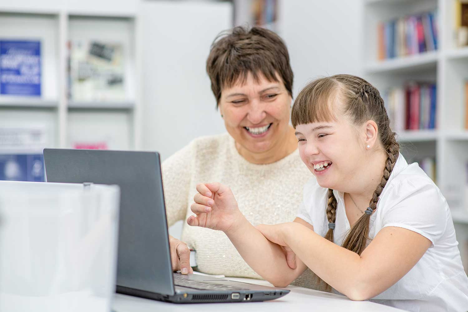 A member of staff sits alongside a pupil with Down's Syndrome