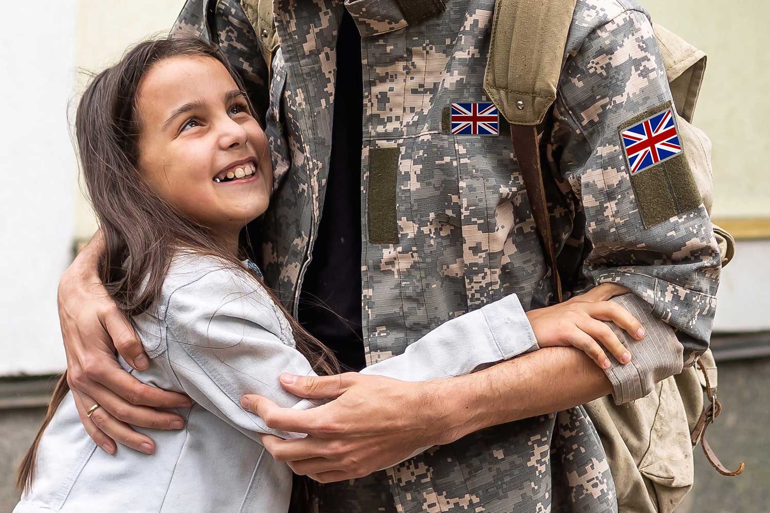 A person wearing military uniform embraces a child