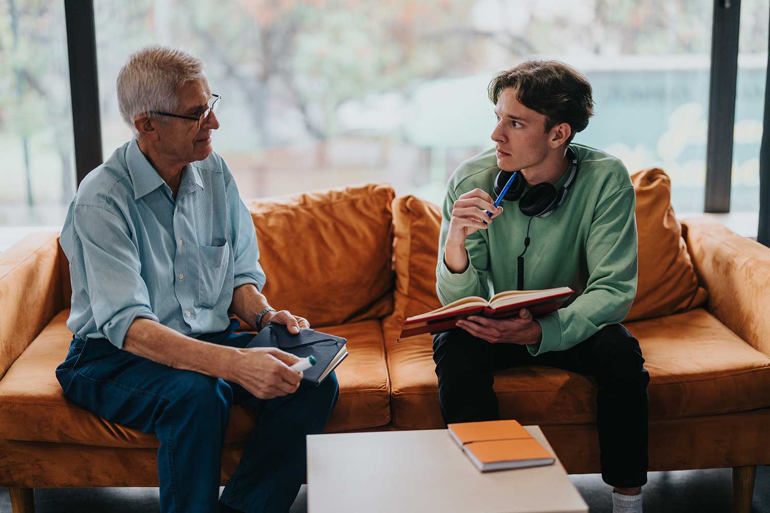 Two men have a serious discussion on a sofa