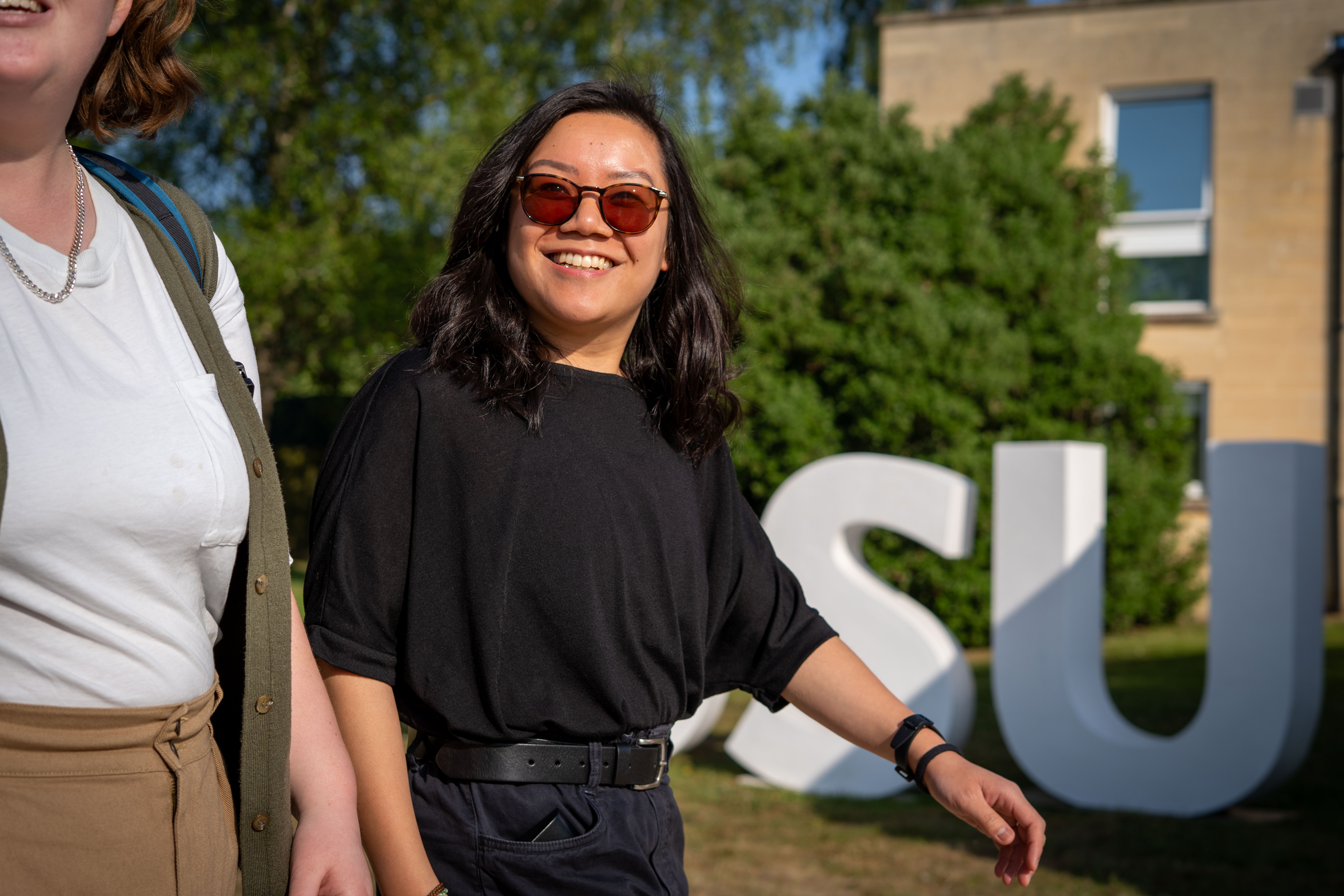 A person wearing sunglasses walks alongside a friend