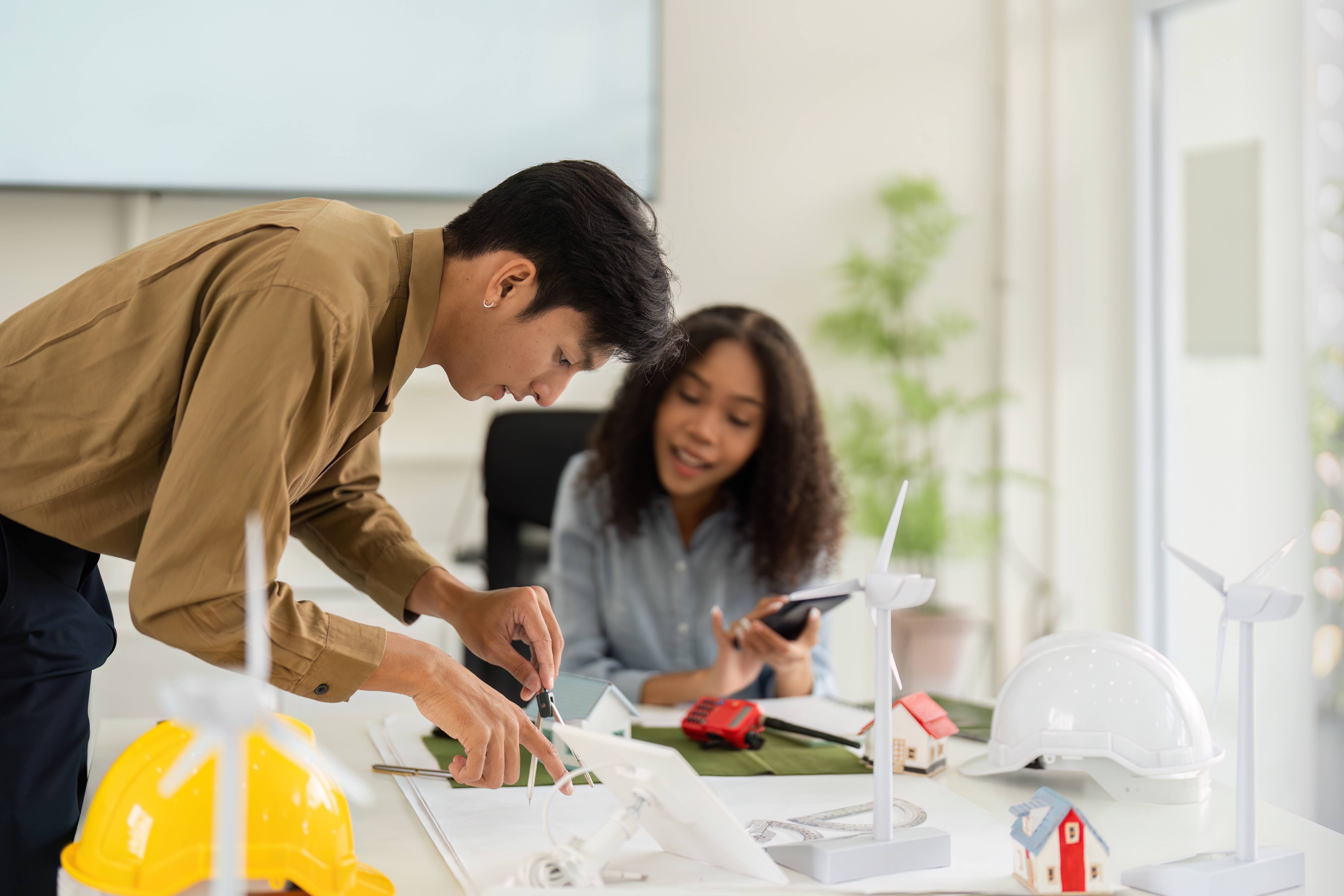 Two workers examine wind turbine designs.