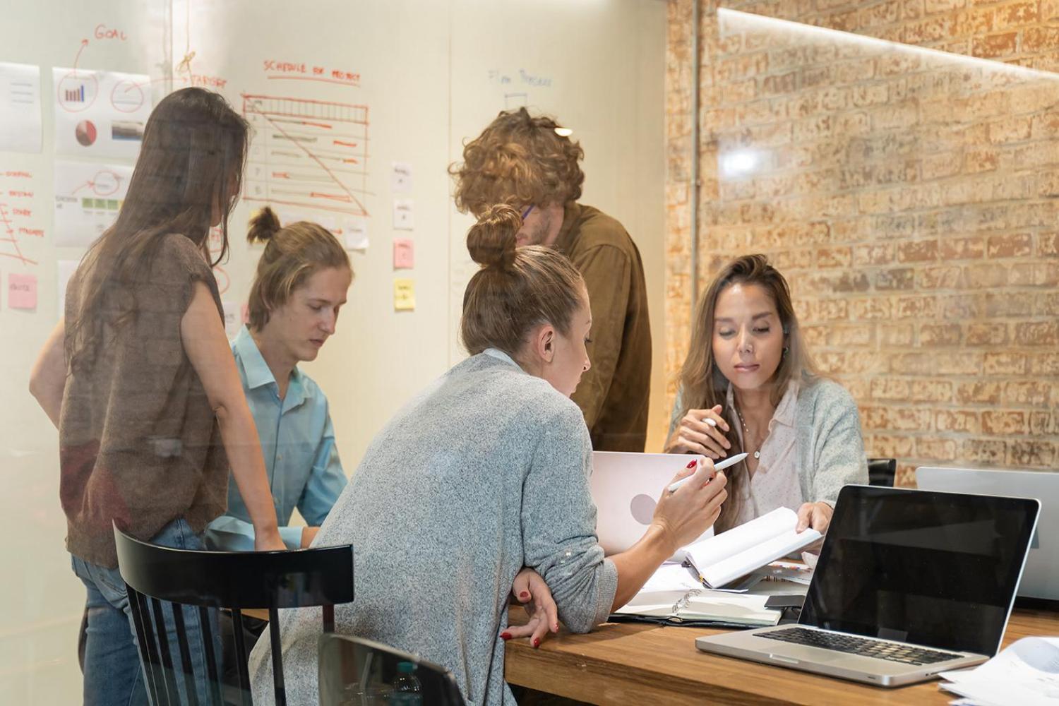 A group of business professionals collaborate around a table in a warmly lit room.