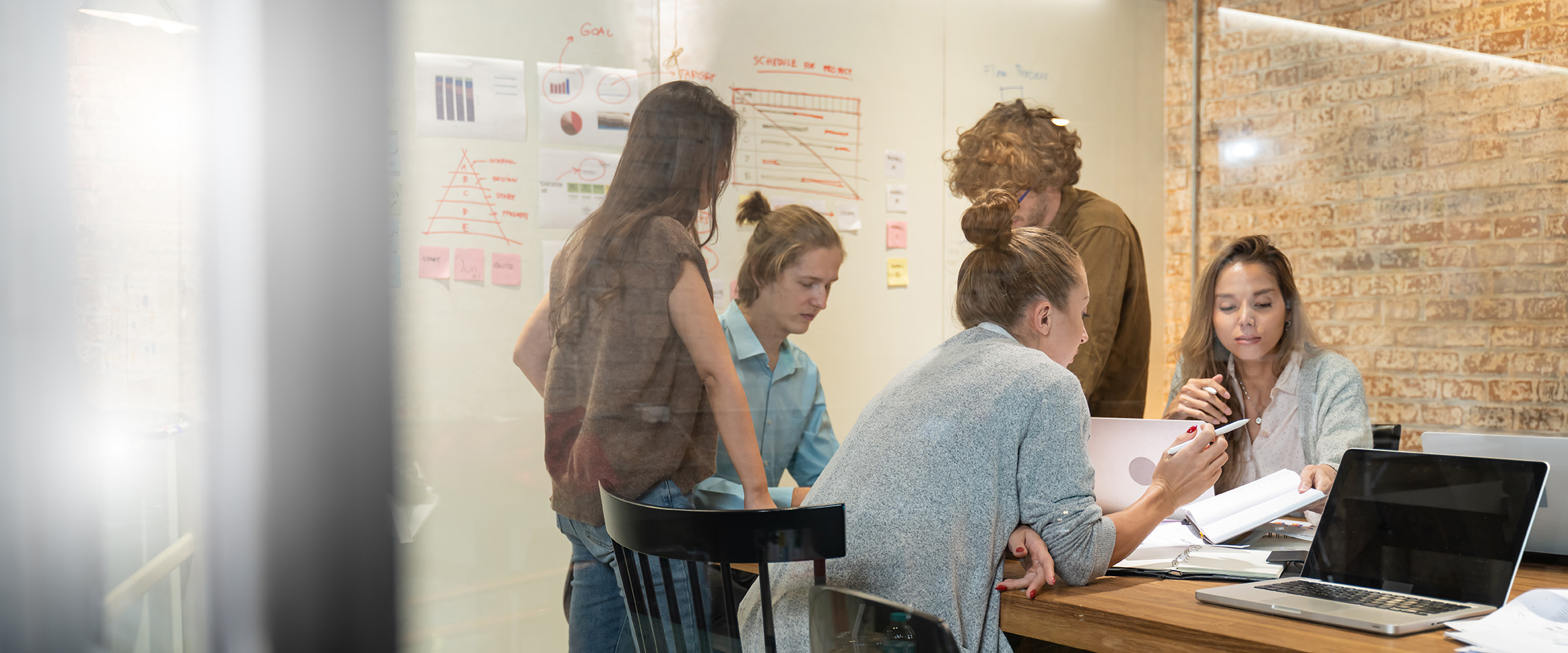 A group of business professionals collaborate around a table in a warmly lit room.