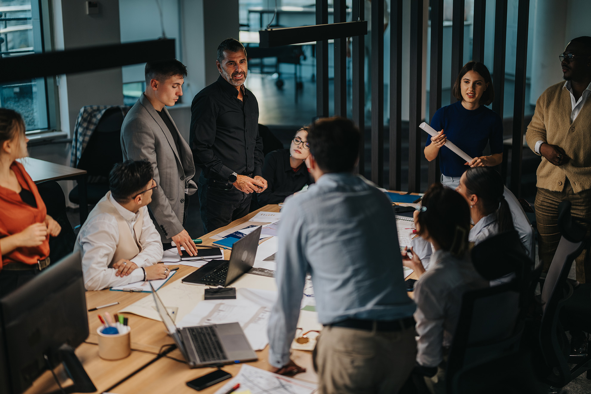 A group of professionals gather around a table in collaboration.