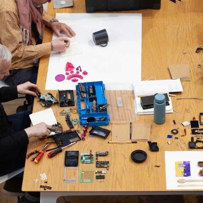 Several people sit at a table and explore the individual components of several objects