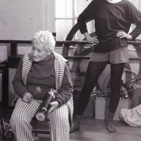 An elderly woman sitting in a chair, teaching a class