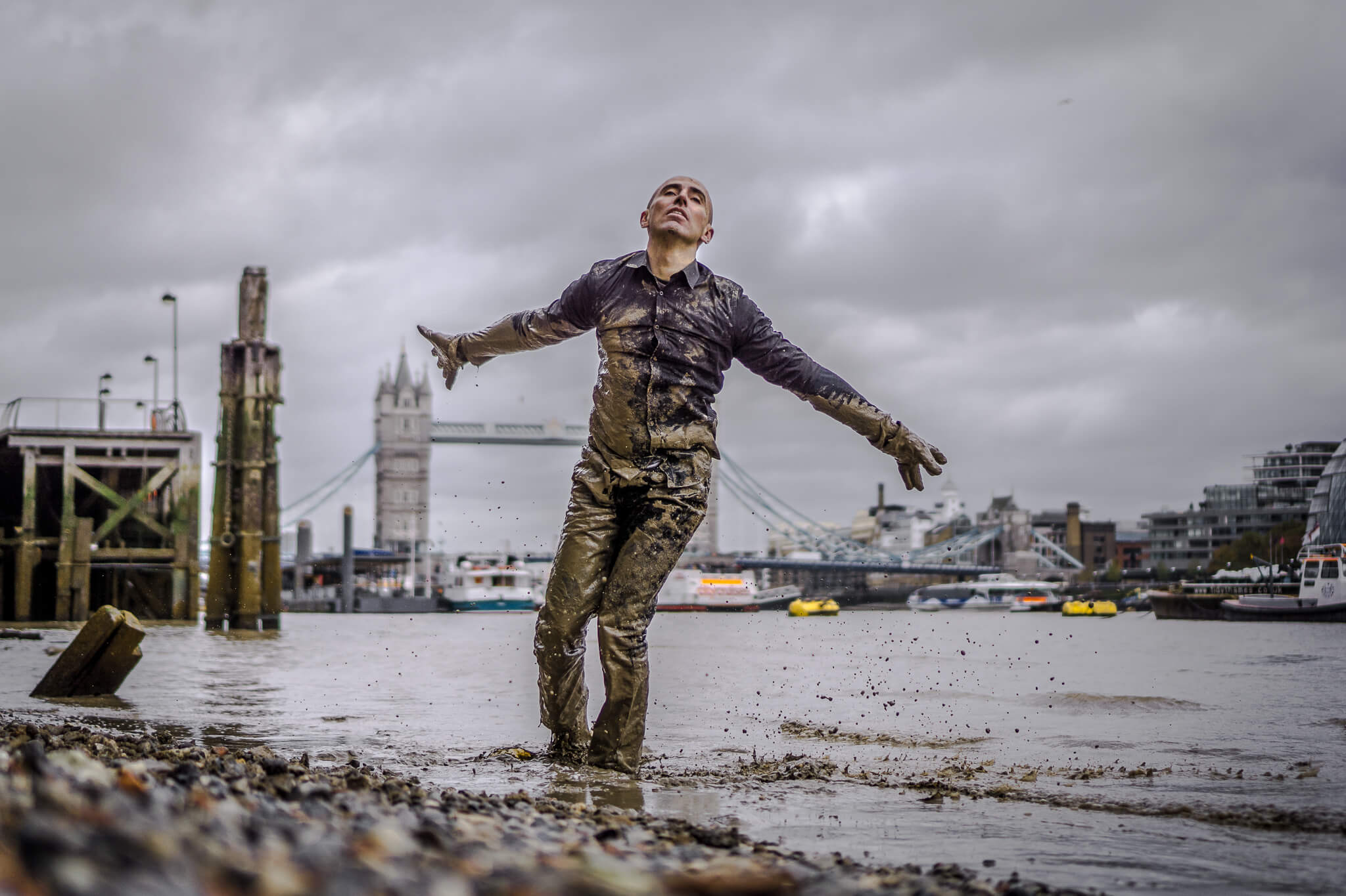 Person covered in mud by the river Thames in London.