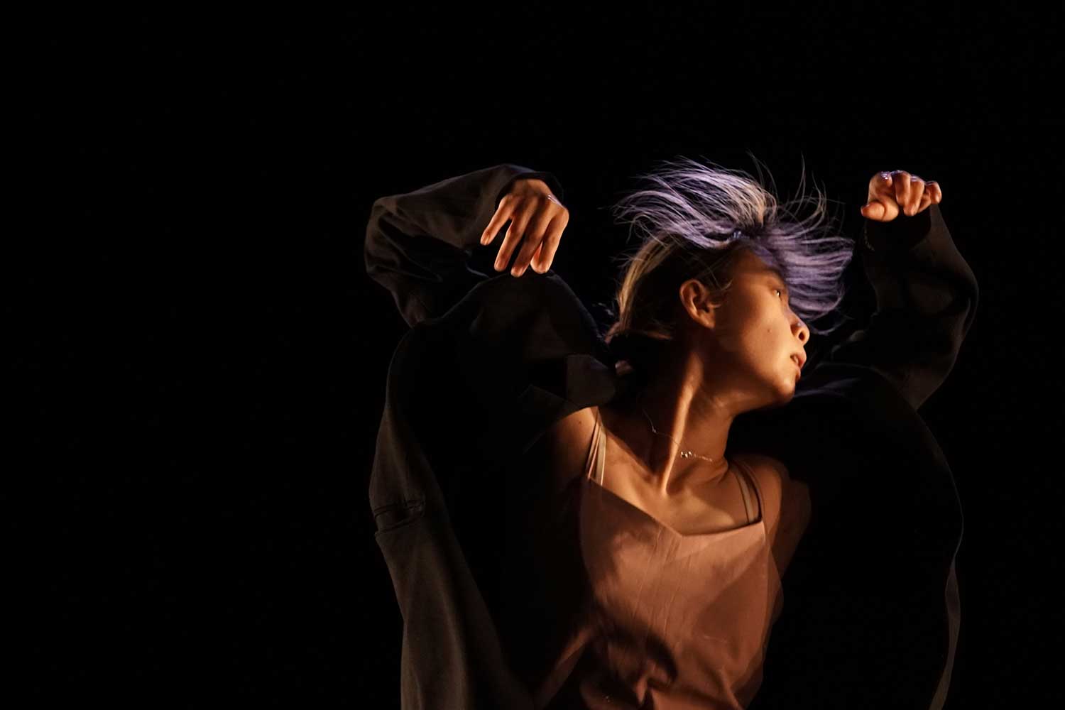 A dancer throws her arms in the air