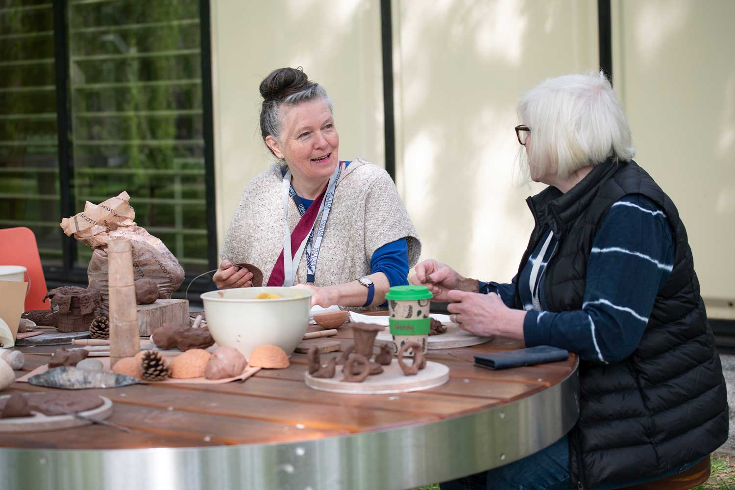 Two people sit outside Locksbrook in a ceramics session