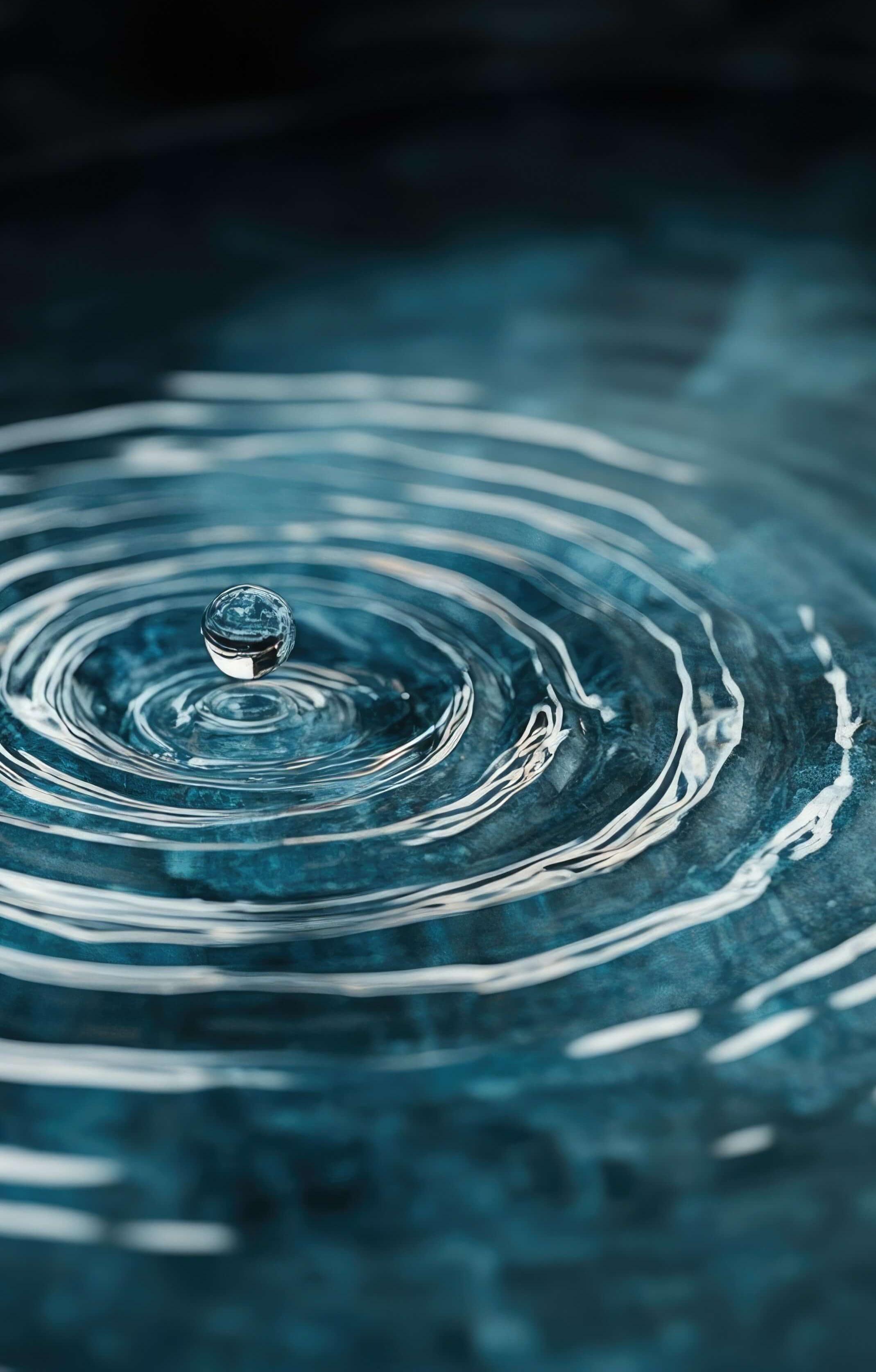 A droplet of water hits the surface of water and causes ripples