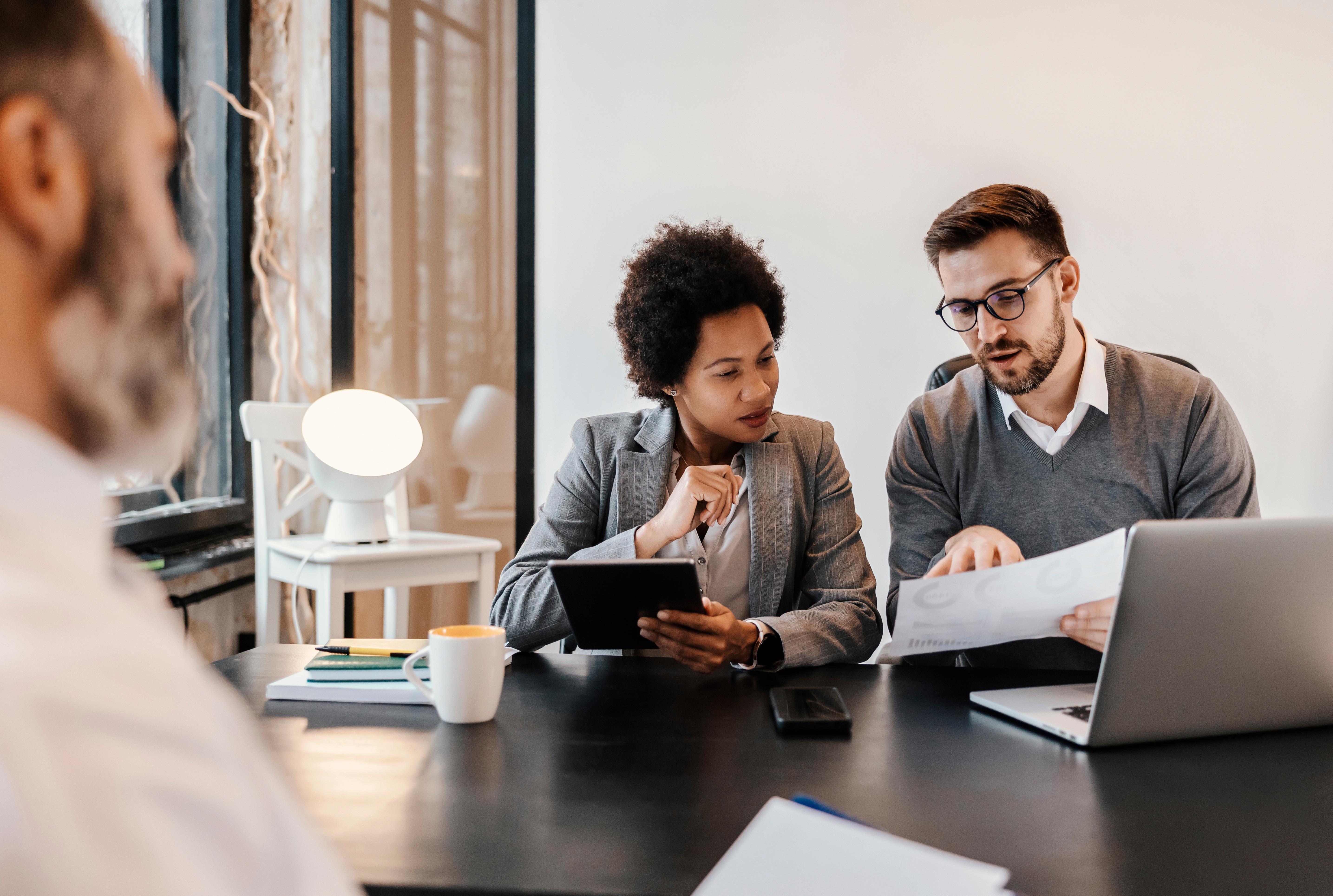 A meeting room table with two people looking at printed graphs on paper