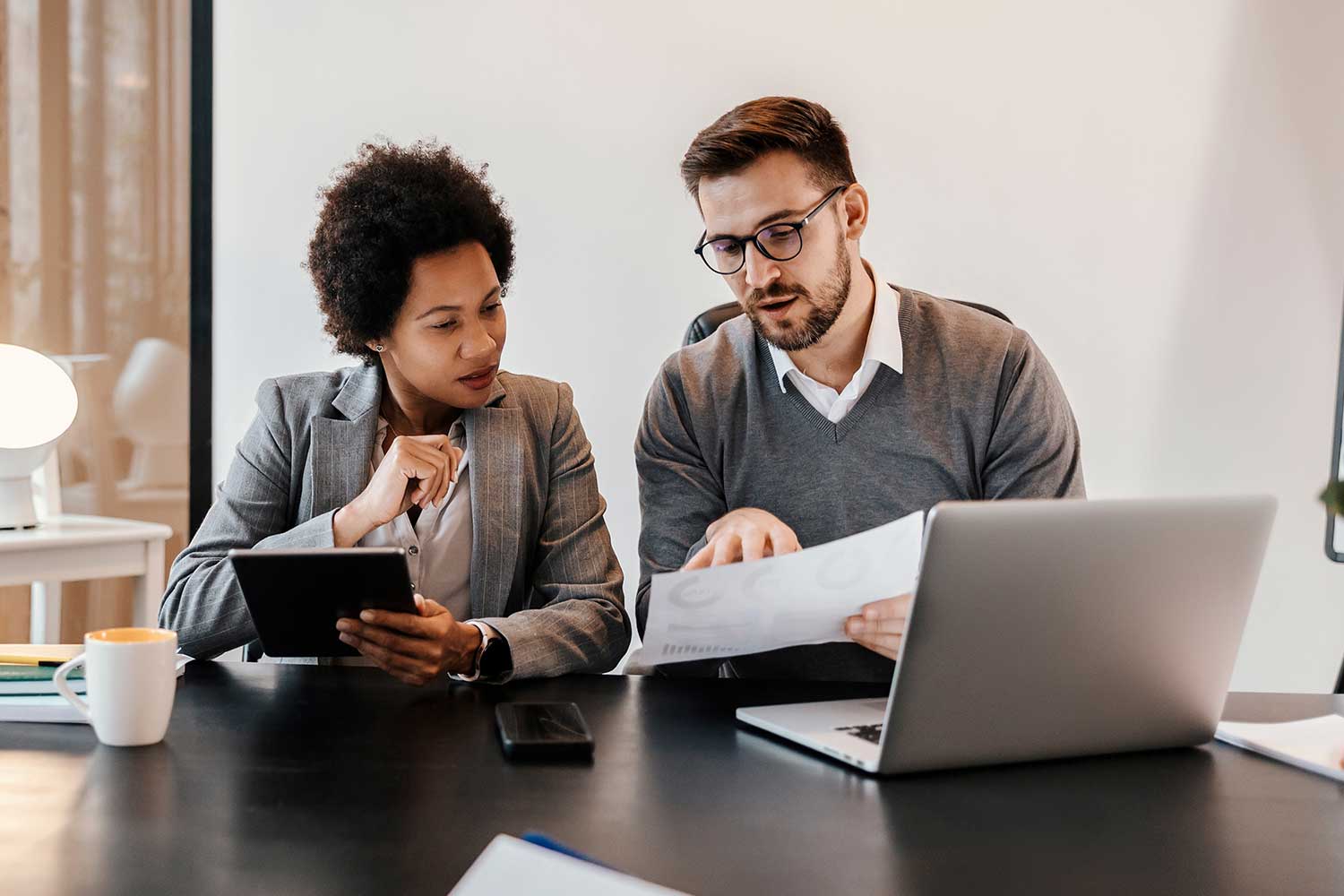 A meeting room table with two people looking at printed graphs on paper