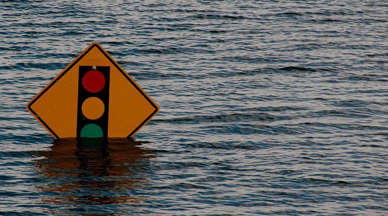 Yellow traffic light sign submerged in flood water.