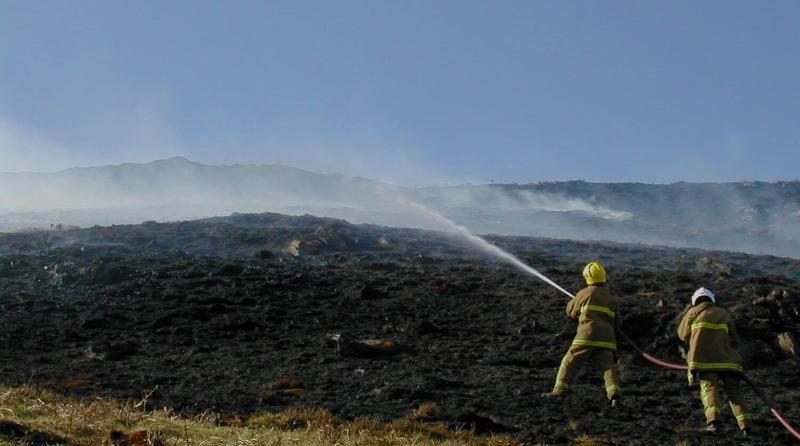 Firefighters spraying water over a blackened moor2