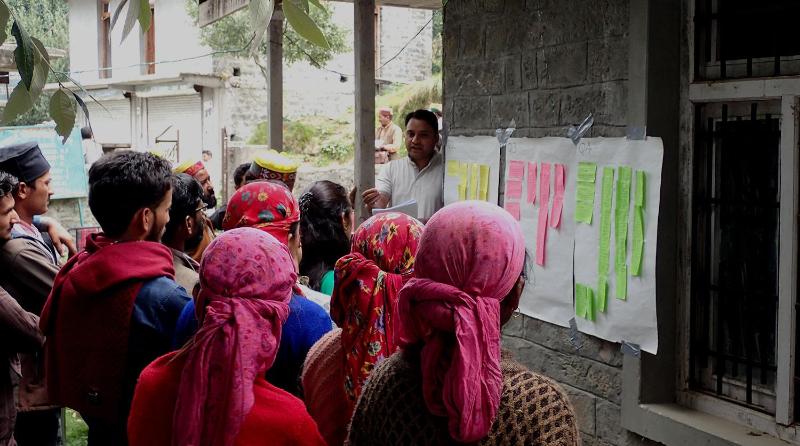 People in coloured headscarves listening to a speaker