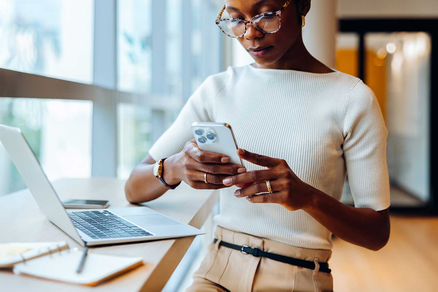 A person wearing smart casual clothing and using their phone