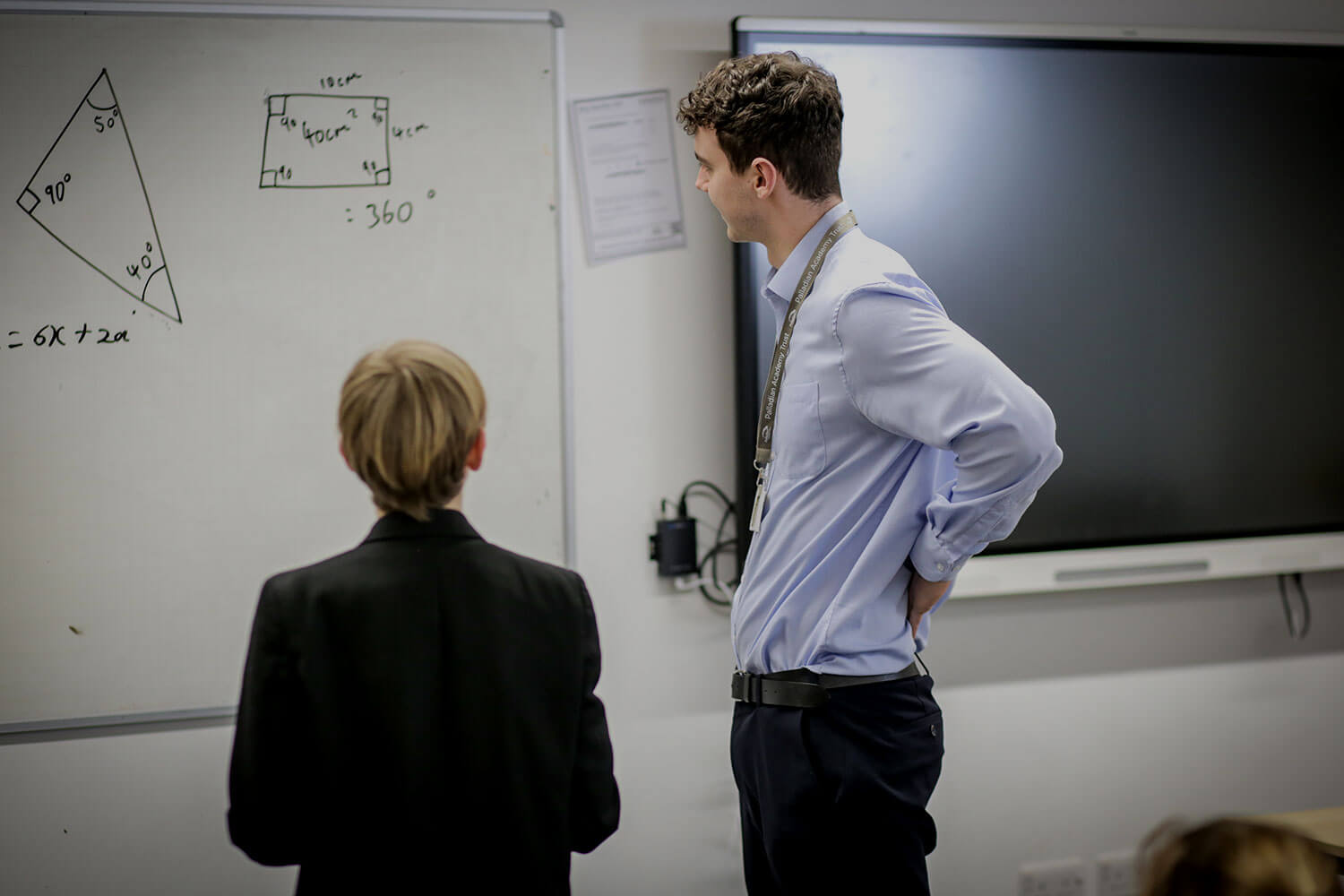 Trainee teacher and pupil looking at a whiteboard